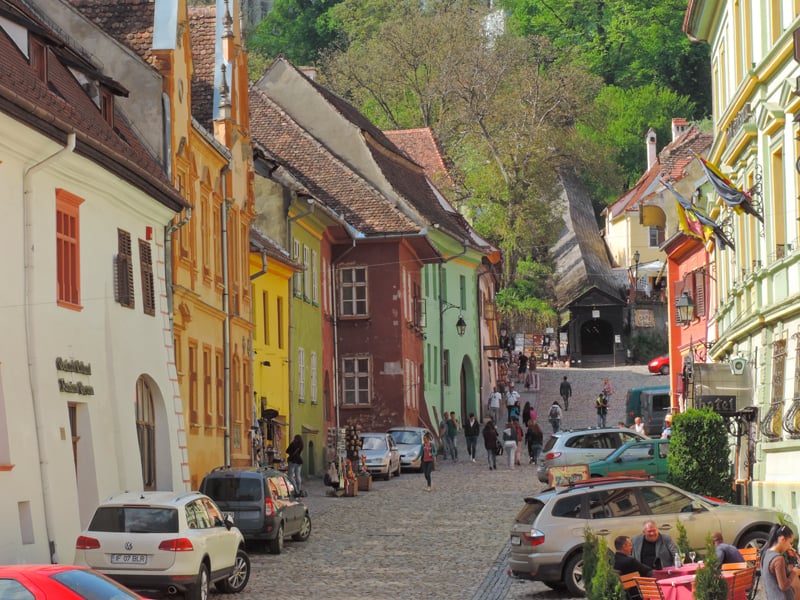 people walking along a colorful medeieval street, one of the things to do in Romania