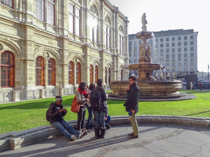 Students standing by a fountain while visiting the opera - one of the things to do in Vienna