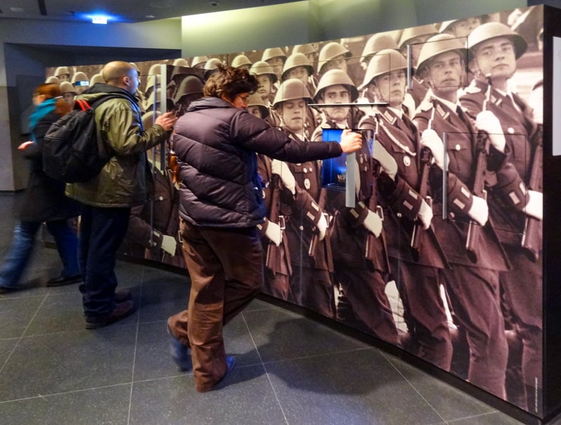 people by an exhibit of marching East German soldiers