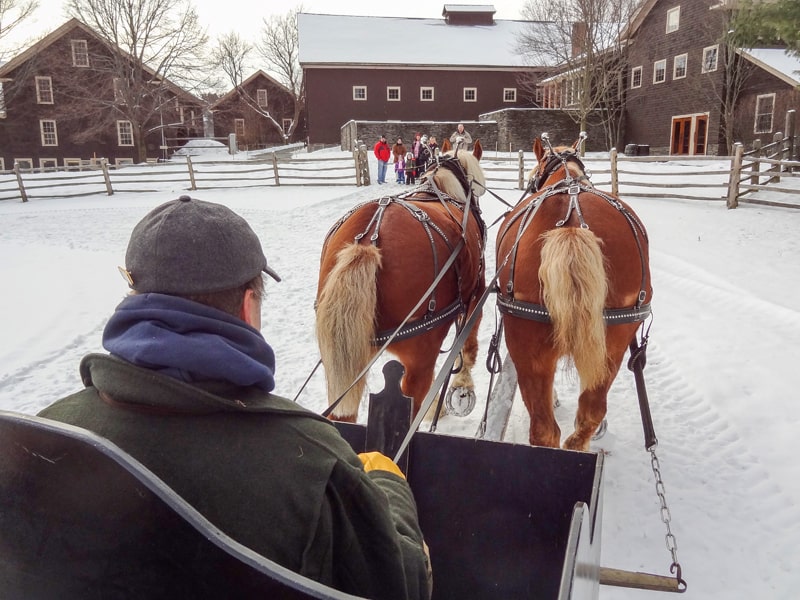 a horse-drawn sled and people by a barn seen on a weekend getaway to Vermont
