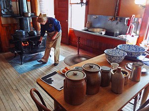 a woman stoking a wood-burning stove in a farmhouse