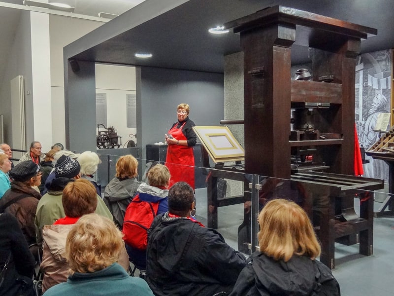 a woman with a red apron giving a demonstration in the Gutenberg Museum, a special European Museums 