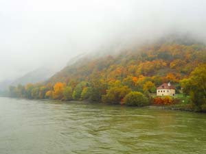 a small house alongside a river in the autumn