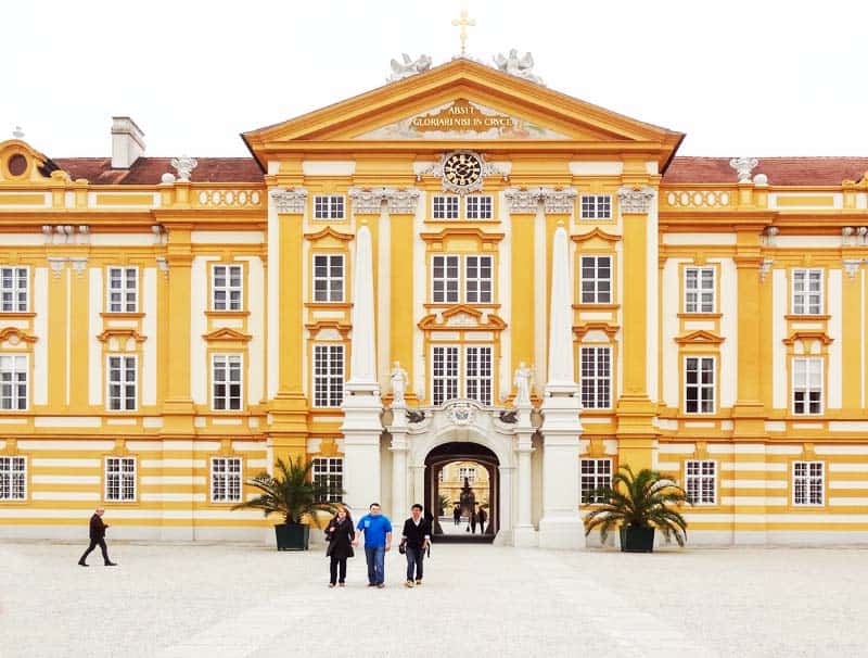 people outside a bright yellow building in Melk Abbey