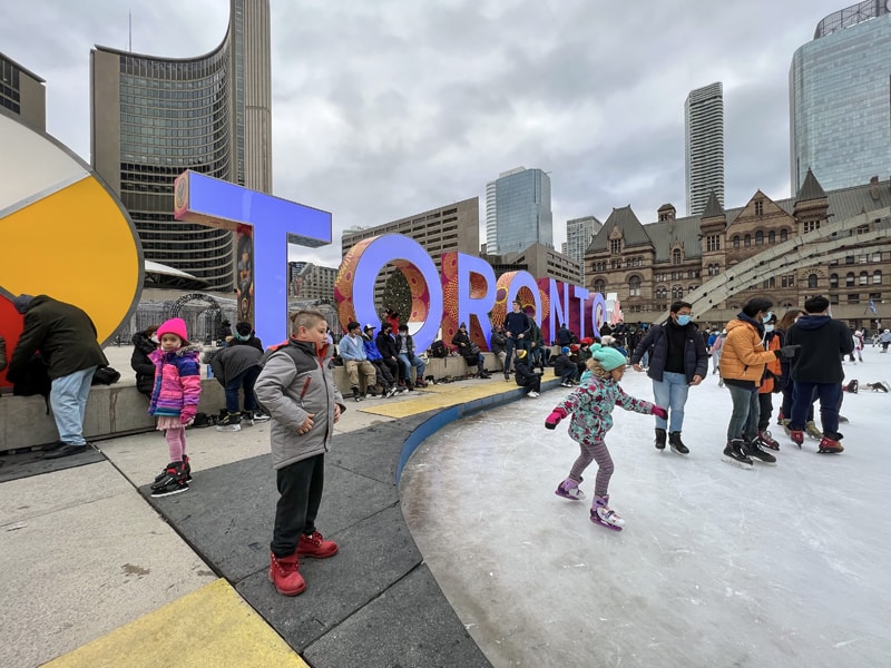 people on ice skates in fron of a large sign that says Toronto