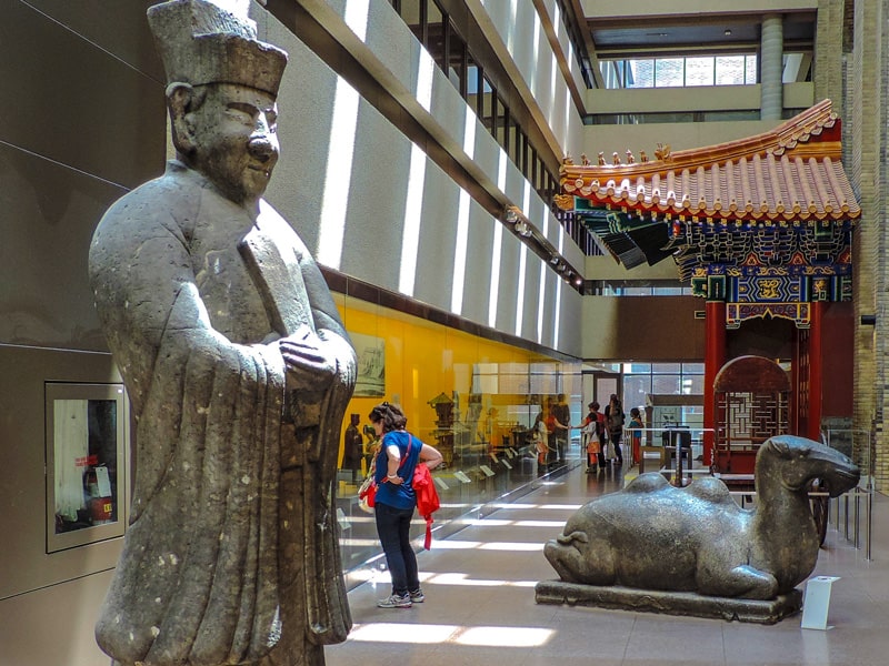 A woman looking at an Asian exhibit in a museum seen in Toronto in the winter