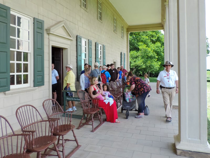 people sitting on the porch of a large house