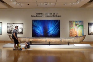 a man and young child by a birchbark canoe in a museum