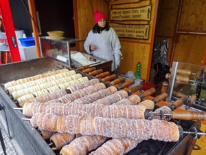 a young woman baking rolls on an outside grill in Prague in winter