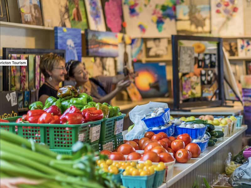 two women selling art and produce in a market