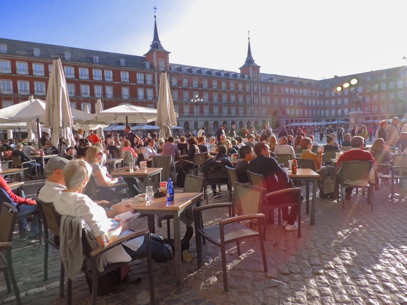 people sitting outside cafes in the Plaza Mayor, one of the things to do in Madrid