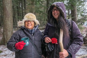 a man and a woman walking through snowy woods