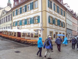 people walking past a building with green shutters in Bamberg Germany