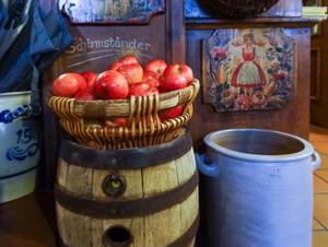 apples in a basket near a large blue jar