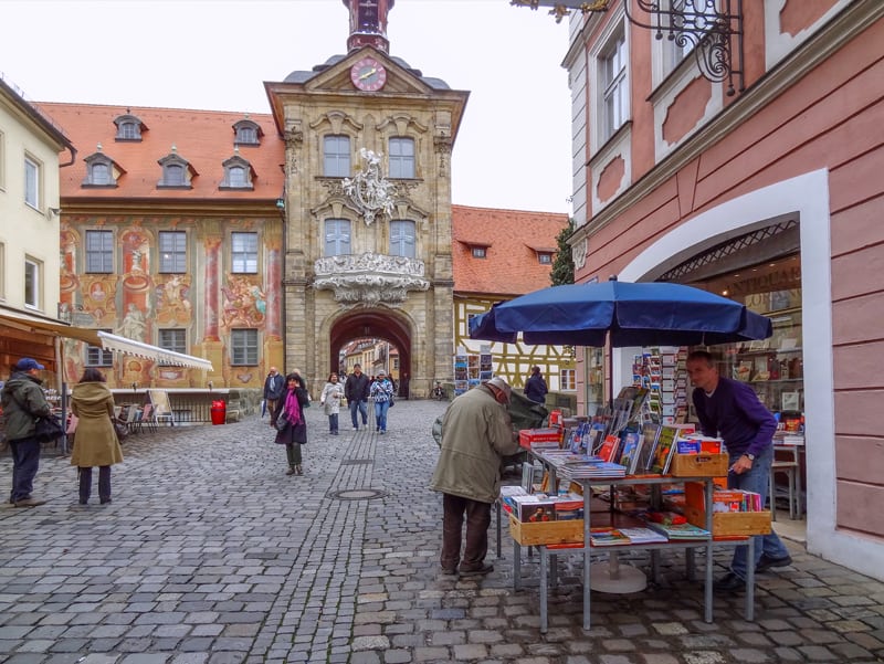 a man selling books near a colorful building in Bamberg Germany