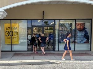 women in shopping mall with a 30% off sale sign in the windown - one of the Things to Do in Orlando for Adults