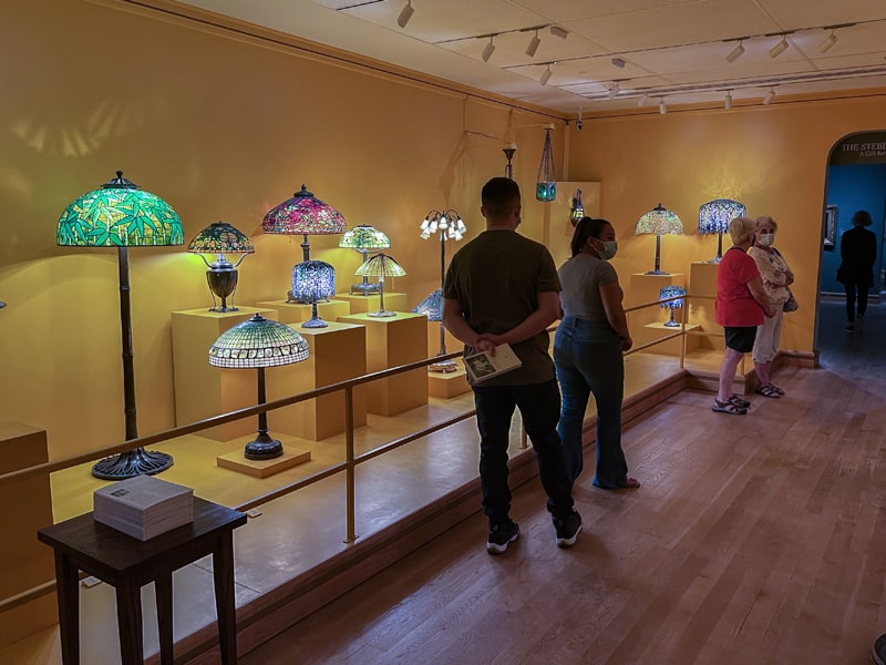 people walking past brightky colored lamps in a museum - one of the Things to Do in Orlando for Adults