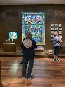 a woman looking at a large stained-glass window in a museum - one of the Things to Do in Orlando for Adults