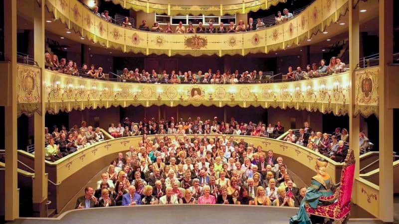 people in a gold-colored theater with three tiers