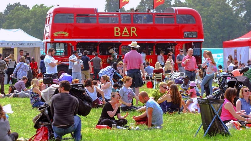 people in front of a large red bus with a bar sign at one of the food festivals in Europe in 2023