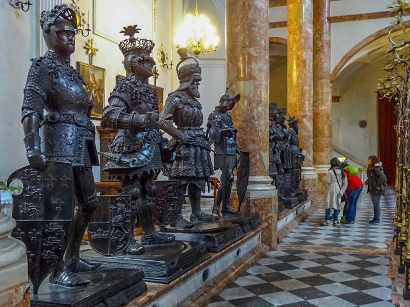 people looking at large black statues in Hofkirche- one of the things to do in Innsbruck