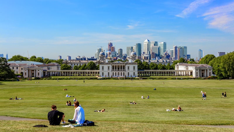 people on a vast lawn looking at a city in the distance - one of the free things to do in London
