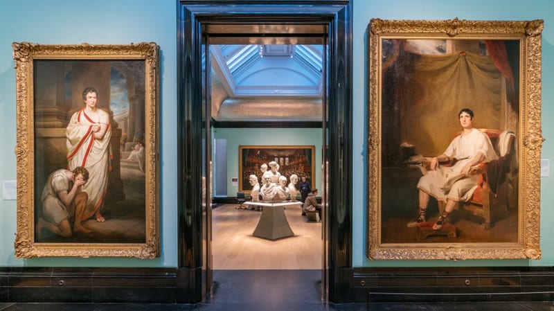 a man looking at paintings in a museum - one of the free things to do in London