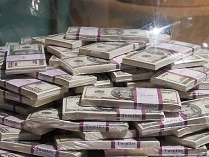 piles of dollar bills with purple bands around them