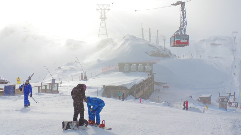 skiers beneath a large red gondola in Zermatt, one of the best places in Switzerland