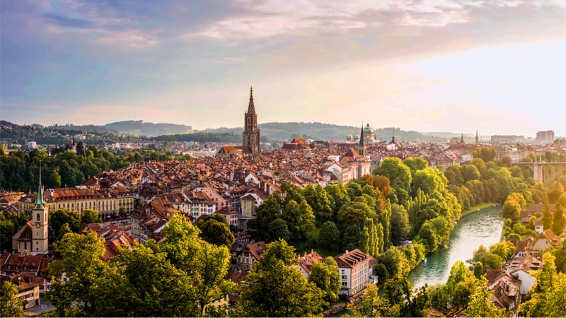 an old European town near a river with many tree along its banks