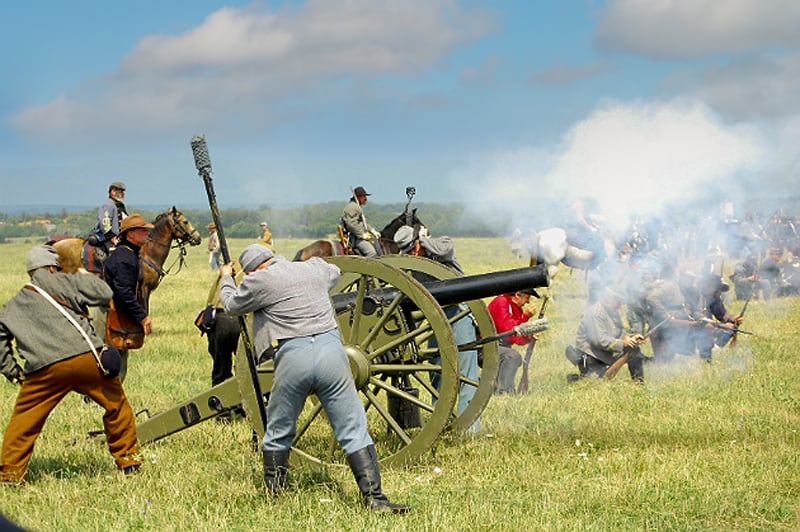 Soldiers in Civil war reenactments firing a canon