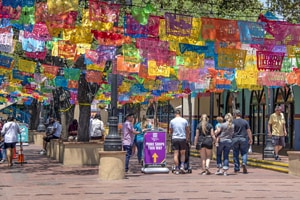 people in a market walking under colorful banners - one of the things to do in San Antonio