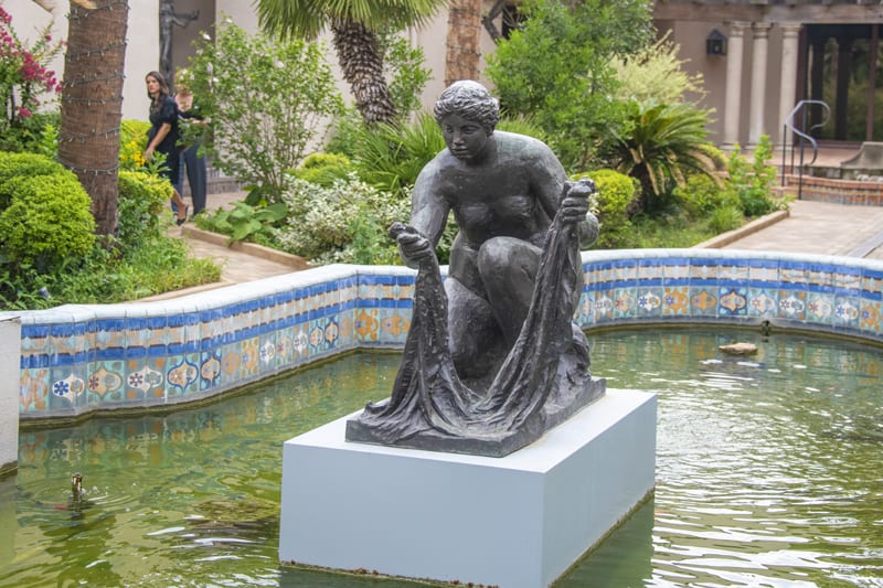 women looking at a statue in a patio pool - one of the things to do in San Antonio