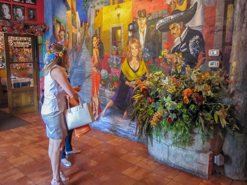 people looking at murals on a wall in a restaurant - one of the things to do in San Antonio