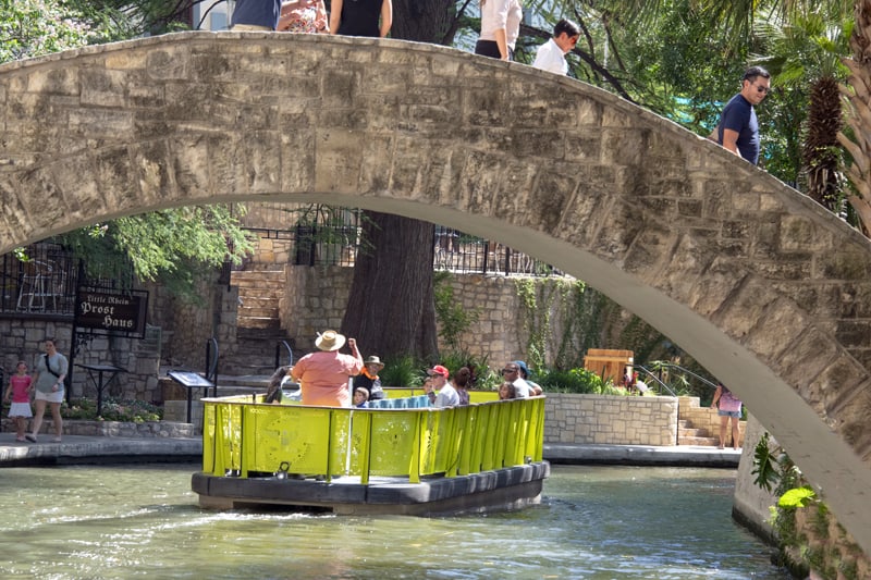 people walking across a bridge on River Walk – one of the things to do in San Antonio