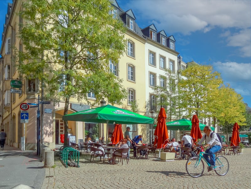 a man bicycling ps a cafe, one of the things to do in Luxembourg