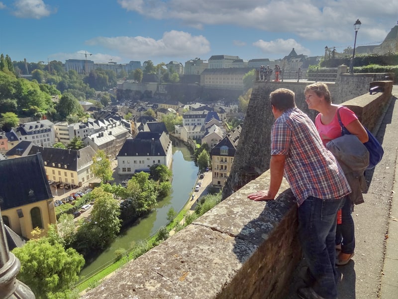 a couple on an old city wall looking at a city, one of the things to do in Luxembourg
