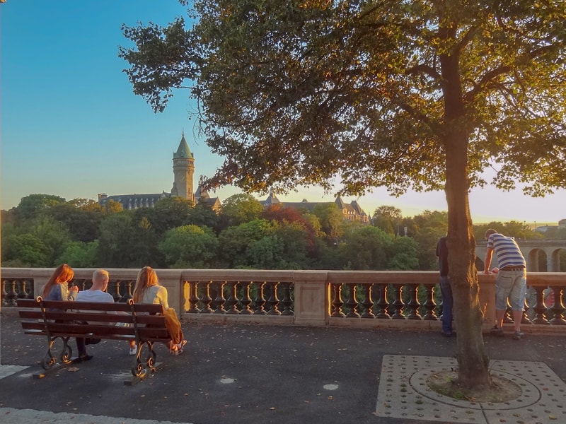 people on a park bench at sunset looking at a castle