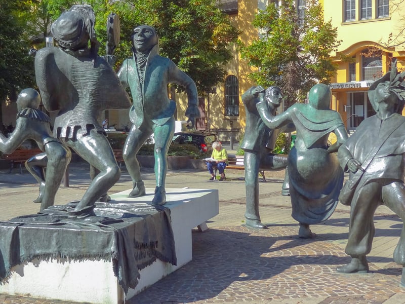 A man looking at stautues of people dancing, one of the things to do in Luxembourg