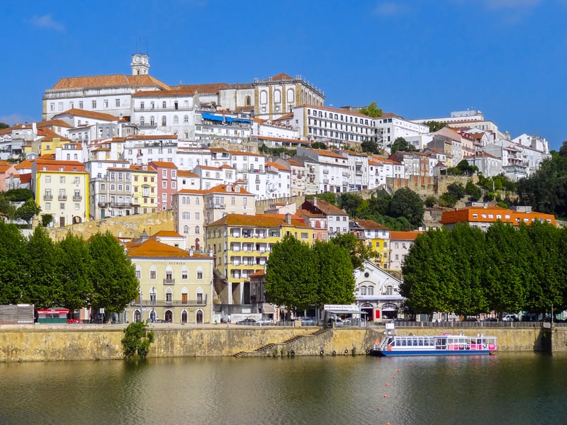 Coimbra, a city of white buildings on a hillside above a river, one of the best places to visit in Portugal