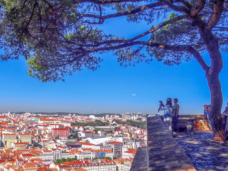 people under a tree on a hillside looking out on Lisbon, one of the best places to visit in Portugal