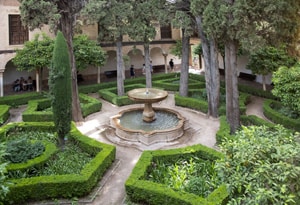a fountain in the middle of a formal garden