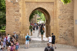 people walking through a large ancient gate in a city wall