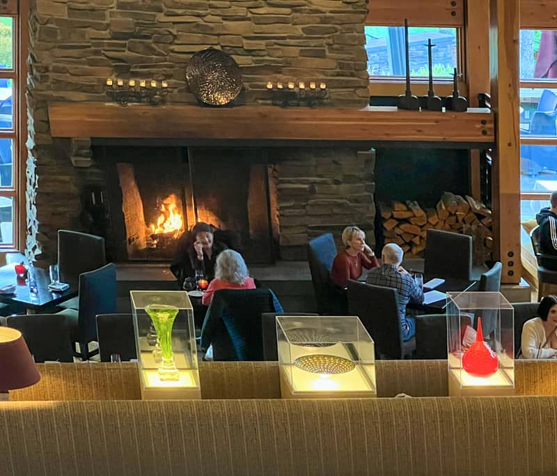 people sitting by a fireplace in a hotel lobby