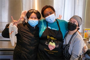 three women waving to the camera at a food hall