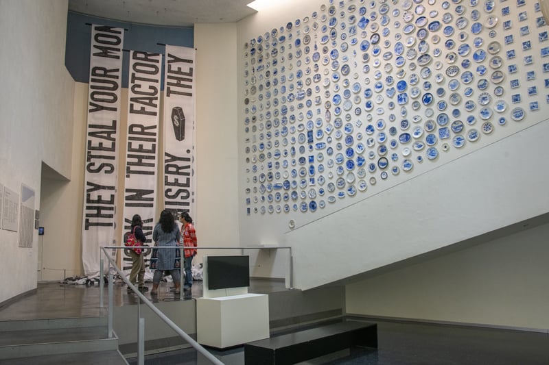 people looking at a large work of art on a museum wall 