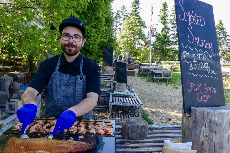 a chef preparing smoked salmon on a charcoal grill 