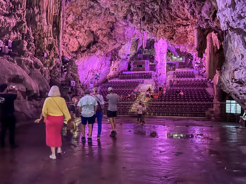 people in a huge cave bathed in purple light - one of the things to do in Gibraltar