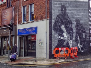 a woman walking past a building that has a mural of soldiers on its side