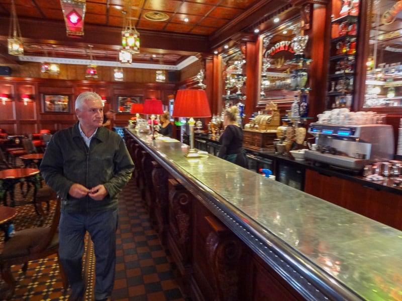 a many walking by a bar in an ornate restaurant - seen on a black taxi tour of Belfast